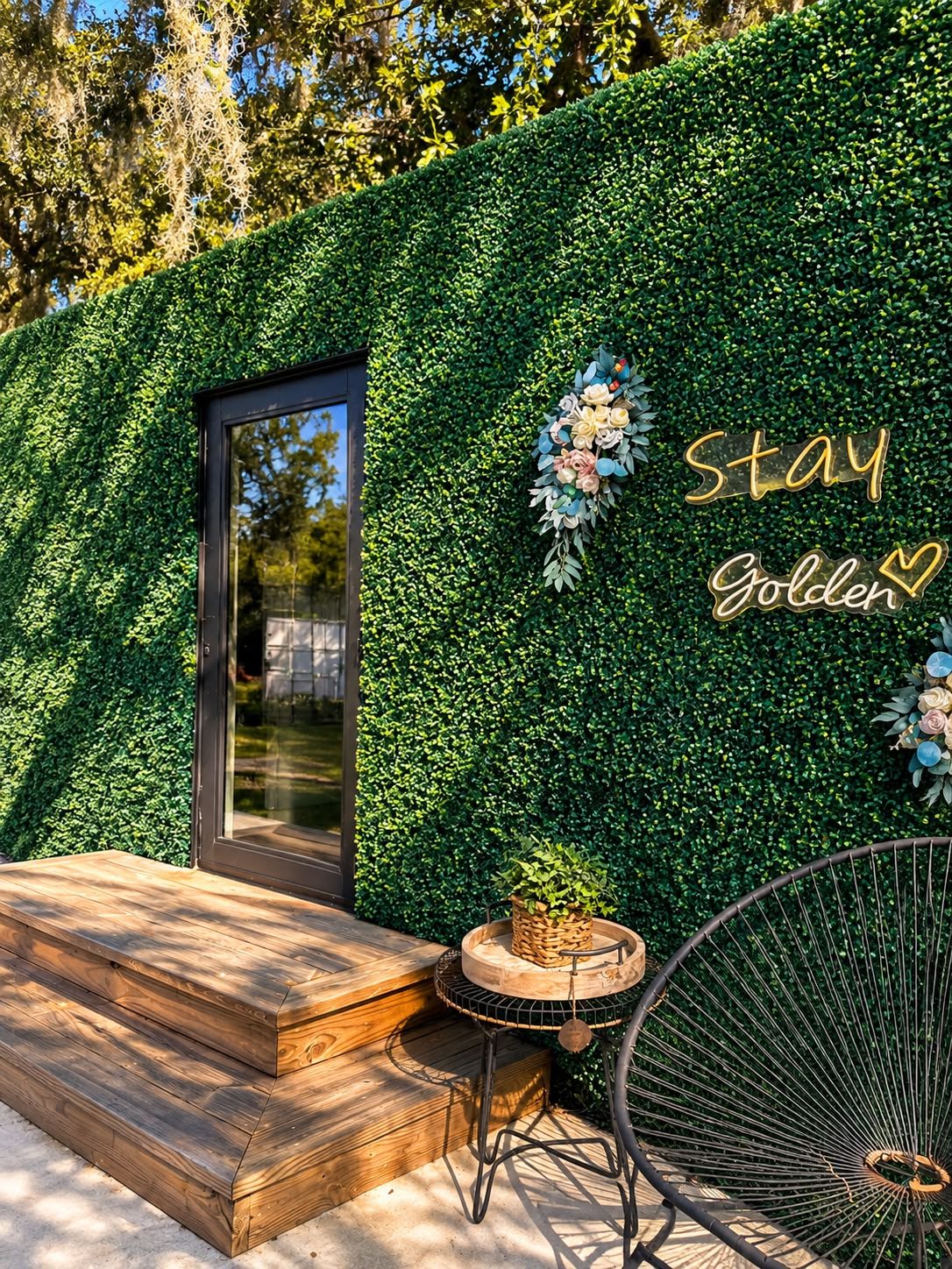 Garden seating nook with woven chairs beside a green foliage wall at CAL Events Cooper City